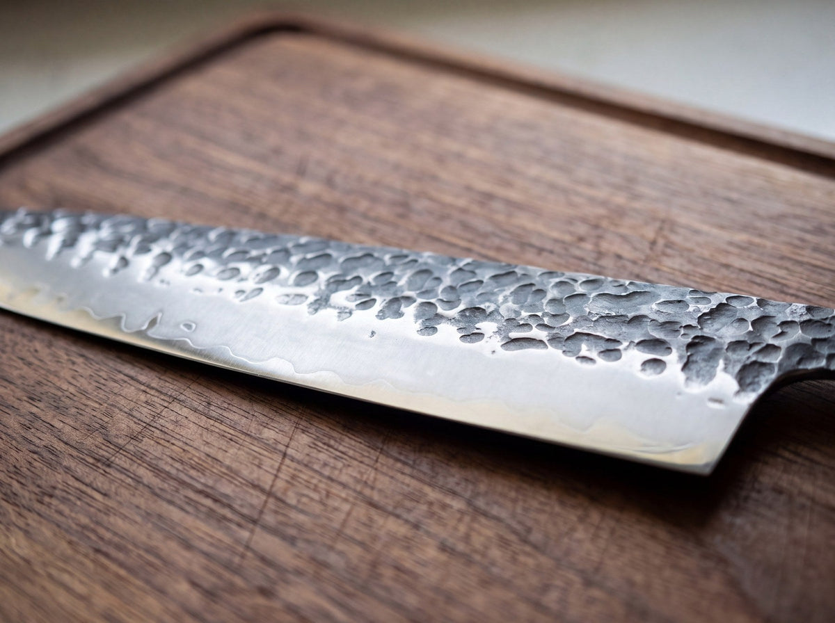 Close-up of a chef knife with a hammered blade finish lying on a walnut cutting board